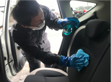 車内シートに消毒液を噴霧しクロスで拭き上げる清掃作業の様子